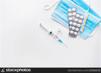 Preparation for vaccination against covid-19. Syringe, vaccine, pills, medical mask on a white table. View from above. Preparation for vaccination against covid-19. Syringe, vaccine, pills, medical mask on a white table. View from above.