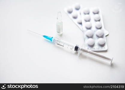 Preparation for vaccination against covid-19. Syringe, vaccine, pills, medical mask on a white table. Preparation for vaccination against covid-19. Syringe, vaccine, pills, medical mask on a white table.