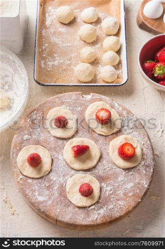 Preparation of cottage dumplings stuffed with fresh strawberries. Cottage dough and fresh berries for summer meals making. Top view. Home cuisine. Cooking with berries. Sweet food