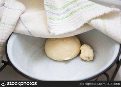 Preparation of dough for making dumplings, ravioli, manti, dumplings. Dough in a plate under a towel. Preparation of dough for making dumplings, ravioli, manti, dumplings. Dough in a plate under a towel.
