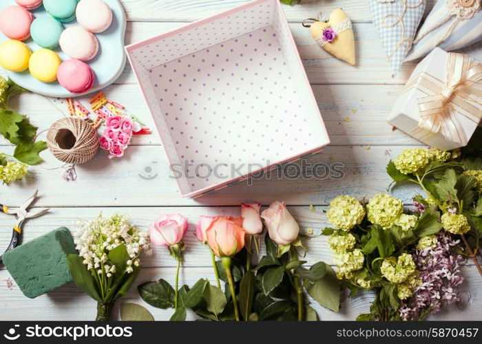 Preparation of flower box with macaroons, top view of florist workplace