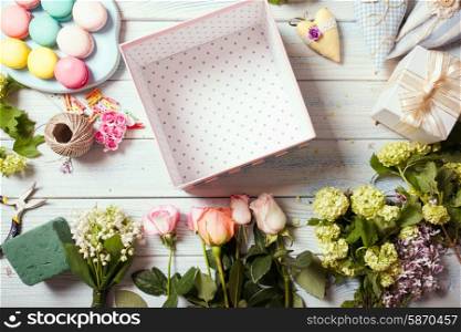 Preparation of flower box with macaroons, top view of florist workplace
