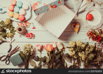 Preparation of flower box with macaroons, top view of florist workplace