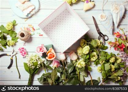 Preparation of flower box with macaroons, top view of florist workplace. Box with flowers and macaroons