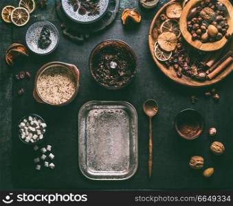 Preparation of homemade vegan chocolate truffle pralines with dried fruits and nuts mix, ingredients on dark background, top view. Healthy sweets. Energy vegan balls with dates, cocoa and almond