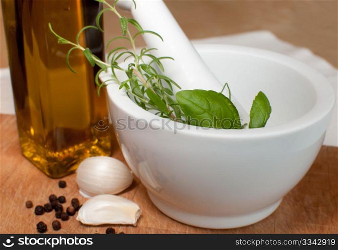 Preparation of marinade in Mortar - Rosemary, basil, garlic, pepper and olive oil on Chopping Board