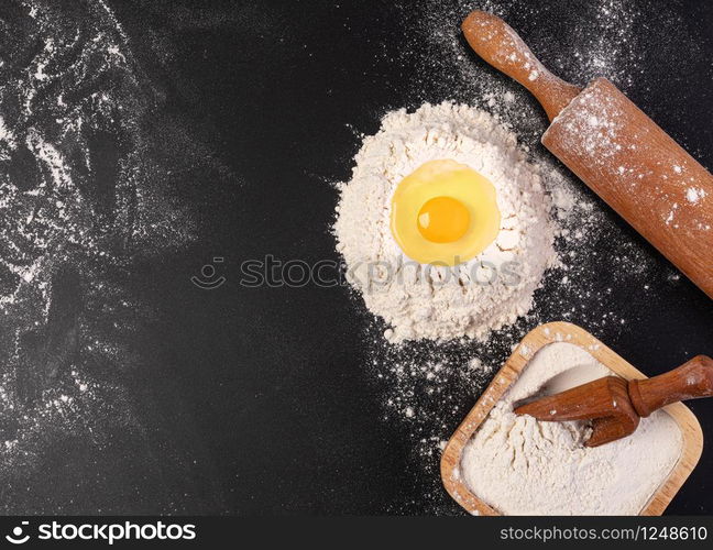 Preparation of the dough. The rolling pin with flour on a dark background. Free space for text.. Rolling pin and white flour on a dark background