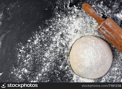 Preparation of the dough. The rolling pin with flour on a dark background. Free space for text.. Preparation of the dough. The rolling pin with flour on a dark background