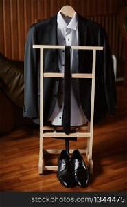 Preparations for the wedding. Groom&rsquo;s jacket on the holder and tie, shoes close to. Morning groom&rsquo;s gatherings on the wedding day. Preparations for the wedding. Groom&rsquo;s jacket on the holder and tie, shoes close to. Morning groom&rsquo;s gatherings on the wedding day.