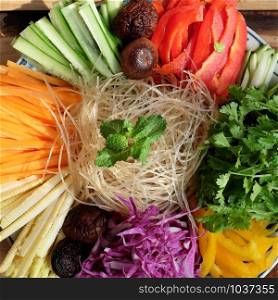 Prepare ingredient food for vegan mixed vermicelli with vegetables, red, yellow bell pepper, purple cabbage, coriander, cucumber, carrot, vegetarian raw material on wooden background