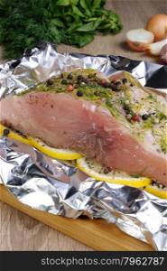Prepared for roasting a piece of raw carp in foil with lemon