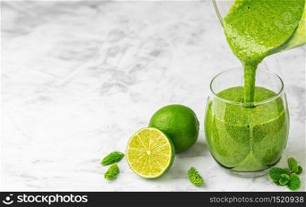 Prepared, healthy detox drink in a blender - a smoothie of fresh fruits, green spinach and superfoods is poured into a glass. Healthy lifestyle concept. close-up
