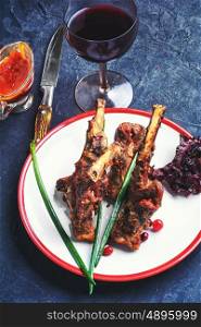 Prepared lamb on the bone. Dish of lamb chops baked in spices and glass of red wine