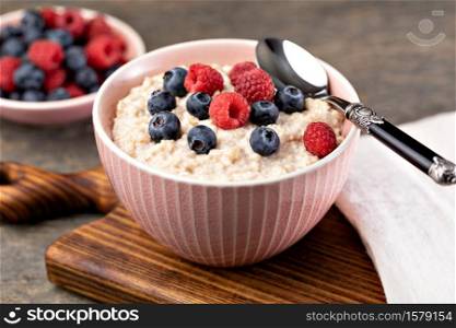 prepared oatmeal with berries on a wooden table. prepared oatmeal with berries