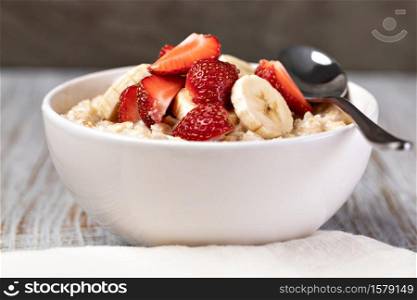 prepared oatmeal with fruits and berries on a wooden table. prepared oatmeal with fruits and berries