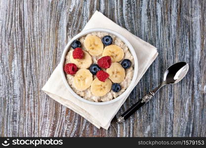 prepared oatmeal with fruits and berries on a wooden table. prepared oatmeal with fruits and berries