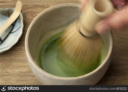 Preparing a bowl of matcha tea with a tea whisk