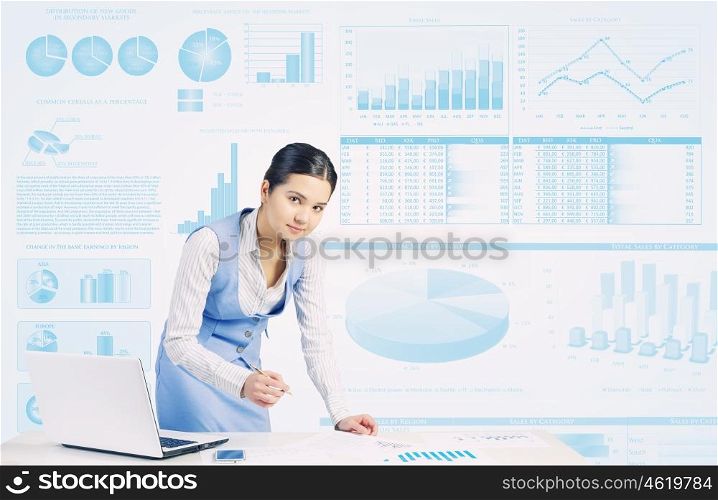 Preparing average report. Businesswoman at table working on laptop and infographs at background