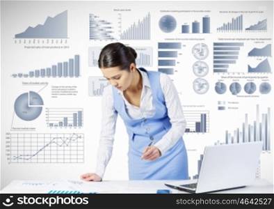 Preparing average report. Businesswoman at table working on laptop and infographs at background