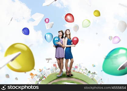 Preparing great party. Two young woman in casual with colorful balloons celebrating