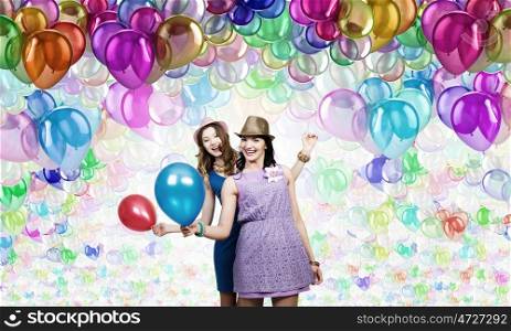 Preparing great party. Two young woman in casual with colorful balloons celebrating