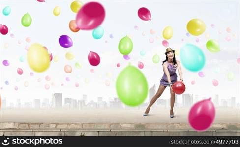 Preparing great party. Young woman in casual with colorful balloons celebrating