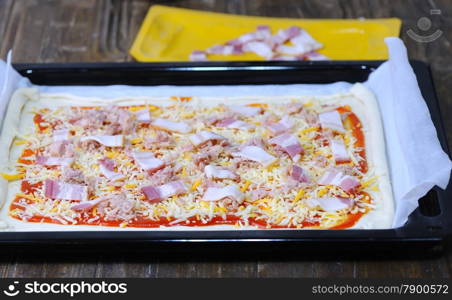 Preparing homemade pizza on wooden table in the kitchen.