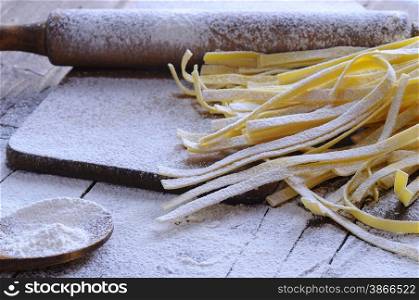 Preparing homemade tagliatelle on wooden table in the kitchen.