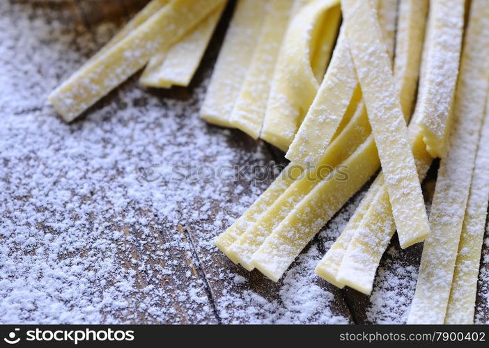 Preparing homemade tagliatelle on wooden table in the kitchen.