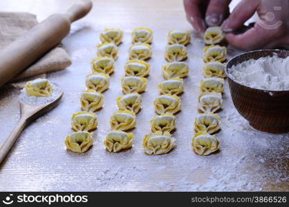 Preparing homemade tortellini on wooden table in the kitchen.&#xA;