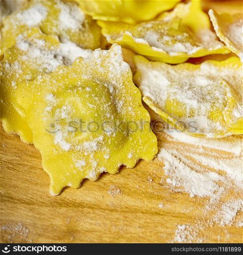 Preparing ravioli in the kitchen with tools and ingredients : dough, flour, eggs, stuffing, cutter, roller, board.