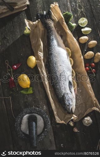 Preparing whole salmon fish for cooking. Vegetables on the table. Vintage style