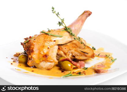Preppared rabbit legs with ham, yellow sauce, green olives and rosemary