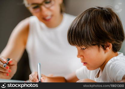 Preschool boy doing school education assessment test. Psychologist asking a questions and preschool boy writing answers.