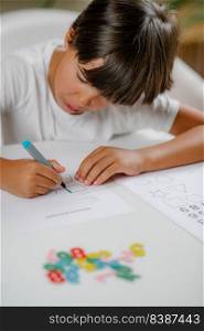 Preschooler boy sitting at the desk, drawing shapes . Preschooler Boy Drawing Shapes