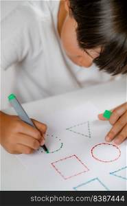 Preschooler boy sitting at the desk, drawing shapes . Preschooler Boy Drawing Shapes