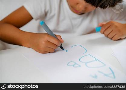 Preschooler boy sitting at the desk, writing letters . Preschooler boy writing letters