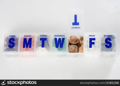 Prescription medication schedule box containing coins and capsules