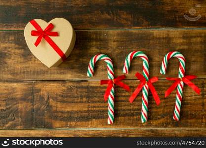 Present for Christmas and Candy Canes with ribbon on a wooden background
