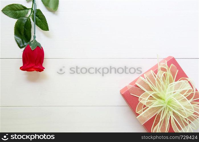 Present gift with red rose flower and gift box with bow ribbon on wooden table, 14 February of love day with romantic, valentine holiday concept, top view.