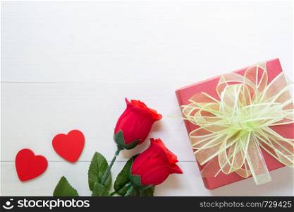 Present gift with red rose flower and gift box with bow ribbon and heart shape on wooden table, 14 February of love day with romantic, valentine holiday concept, top view.