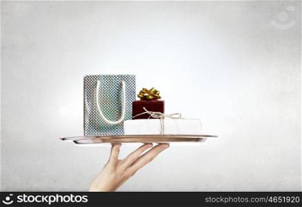 Present on metal tray. Hand presenting gift box on silver tray