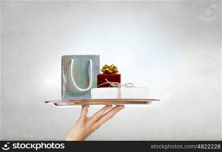 Present on metal tray. Hand presenting gift box on silver tray