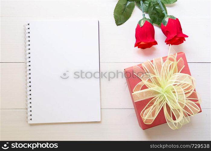 Present red rose flower and notebook and gift box with copy space on wooden table, 14 February of love day with romantic, valentine holiday concept.