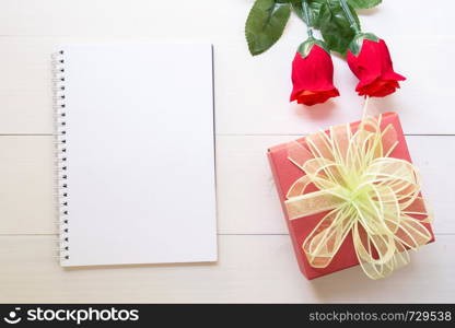 Present red rose flower and notebook and gift box with copy space on wooden table, 14 February of love day with romantic, valentine holiday concept.