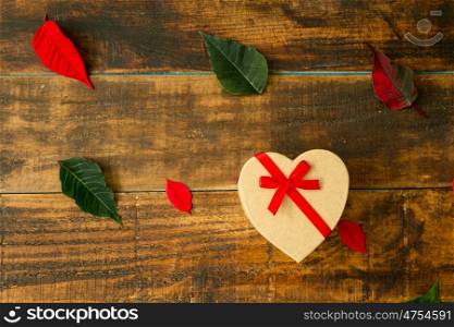 Present with heart shape green and red leaves on a wooden background