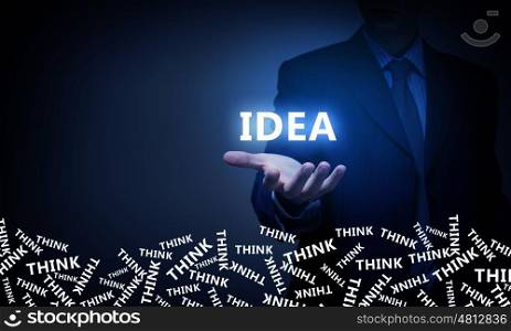 Presenting bright idea. Businessman on dark background holding glowing idea in palm