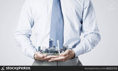 Presenting development project. Close up of businessman holding in hands construction model