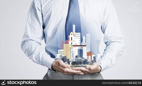 Presenting development project. Close up of businessman holding in hands construction model