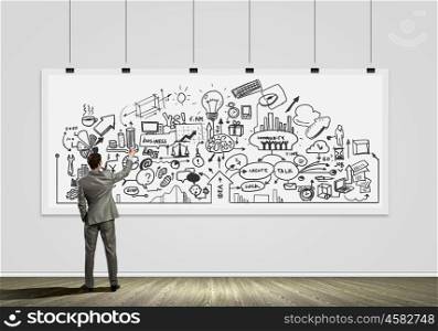 Presenting ideas. Rear view of businessman drawing business plan on white banner